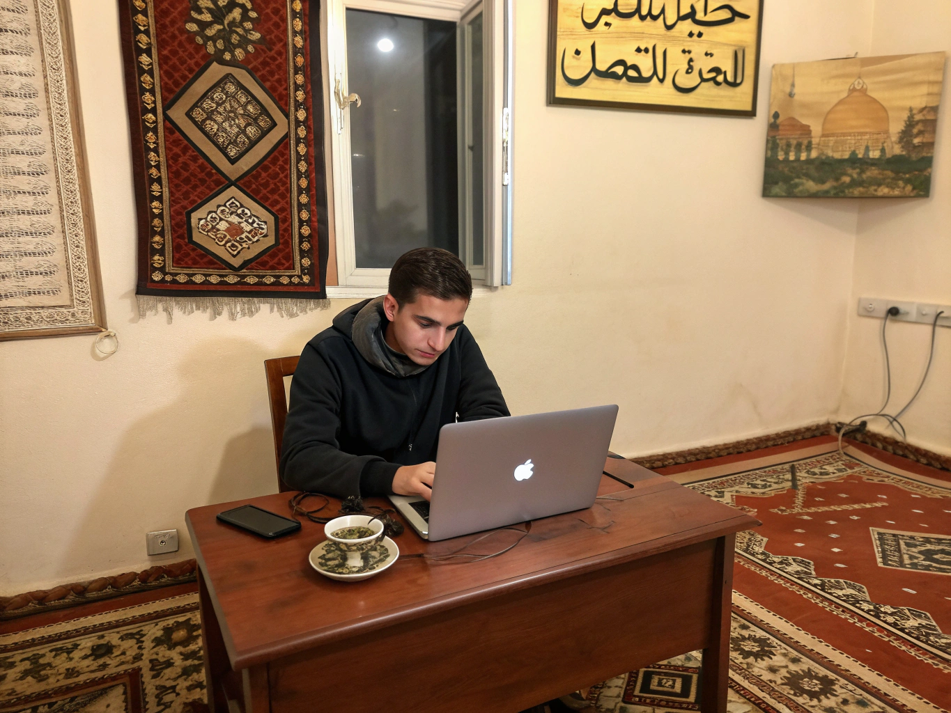 مستقل عربي يعمل على حاسوبه المحمول في بيئة عمل مريحة